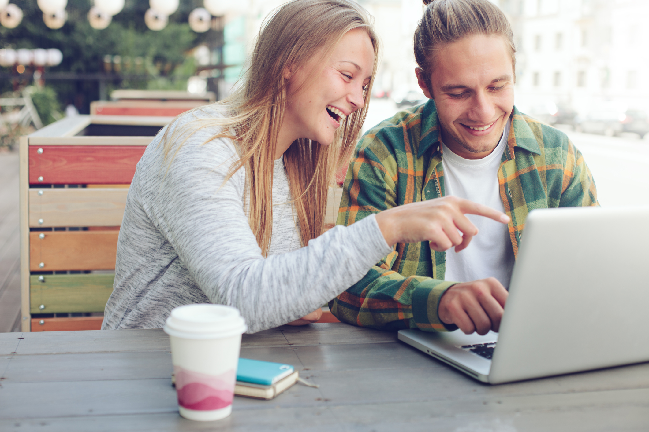 Man and woman sitting in street cafe with laptop