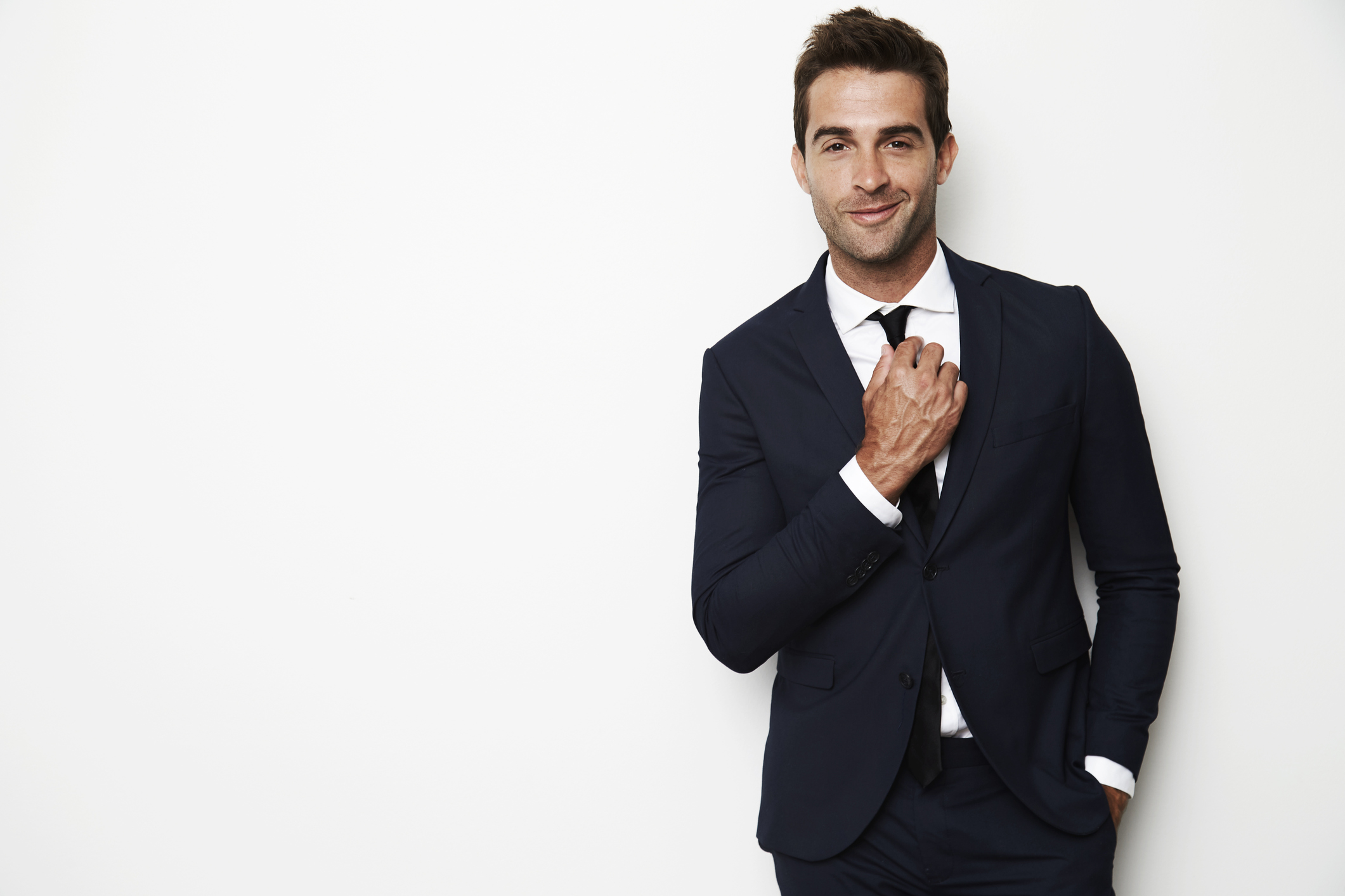 Handsome businessman adjusting tie, smiling